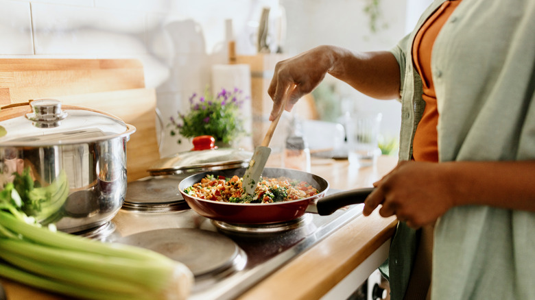 person cooking vegetables on stove