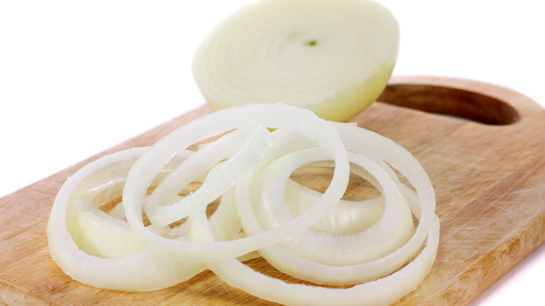 A partially sliced onion on a cutting board