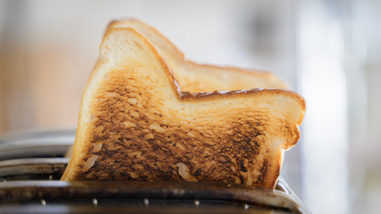 Dark brown toast popping out of toaster