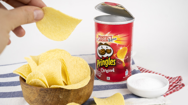 Person holding Pringle with container