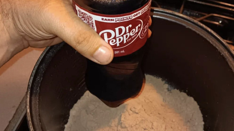 Person holding a bottle of Dr Pepper next to a bowl of brownie mix