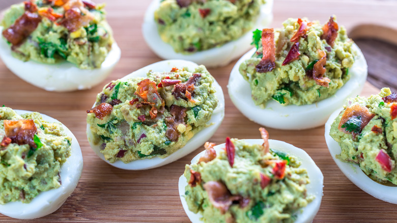 Deviled eggs topped with avocado and bacon