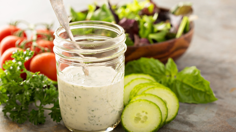 homemade ranch dressing in jar surrounded by salad