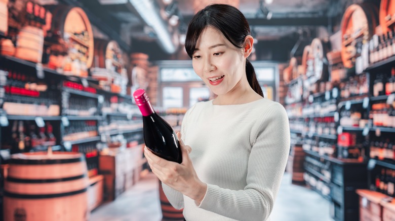 woman choosing red wine in store