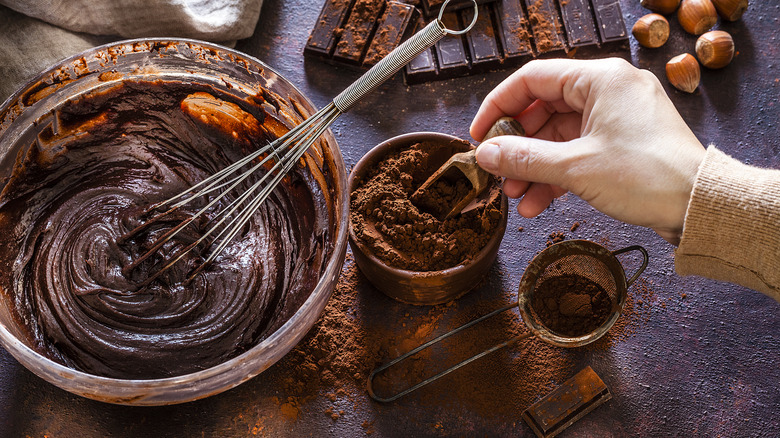 person making chocolate cake batter with cocoa and whisk