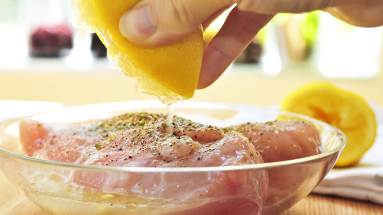 Hand squeezing lemon onto chicken