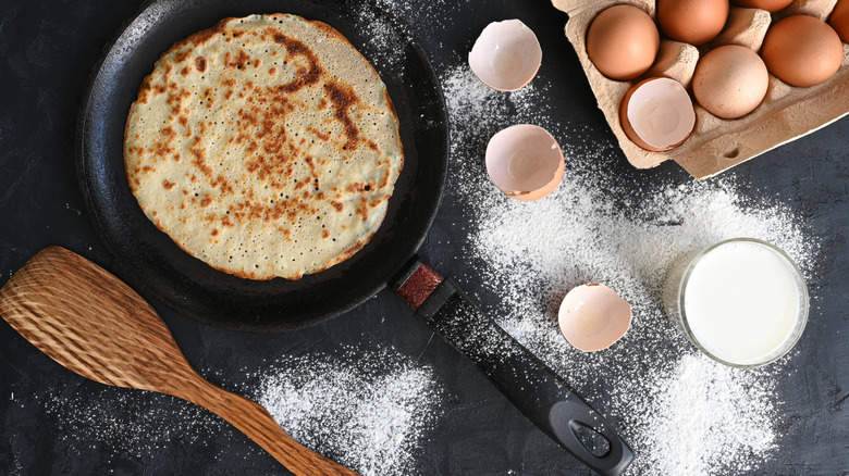 A pancake in a pan surrounded by ingredients