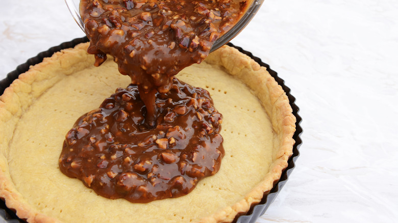 pouring pecan pie filling into pie shell