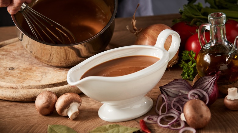 Dark brown gravy on the table with onions and mushrooms