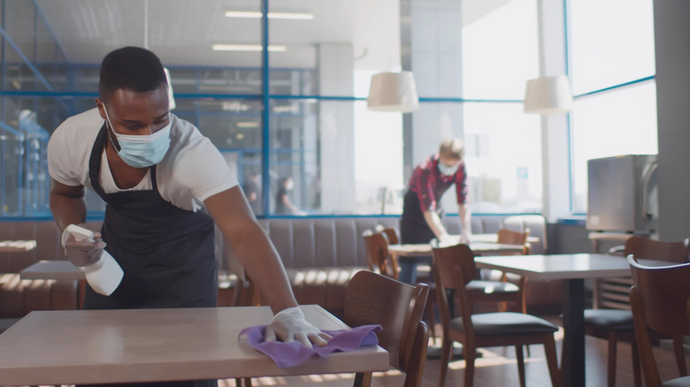 Restaurant workers wearing face masks and wiping down tables