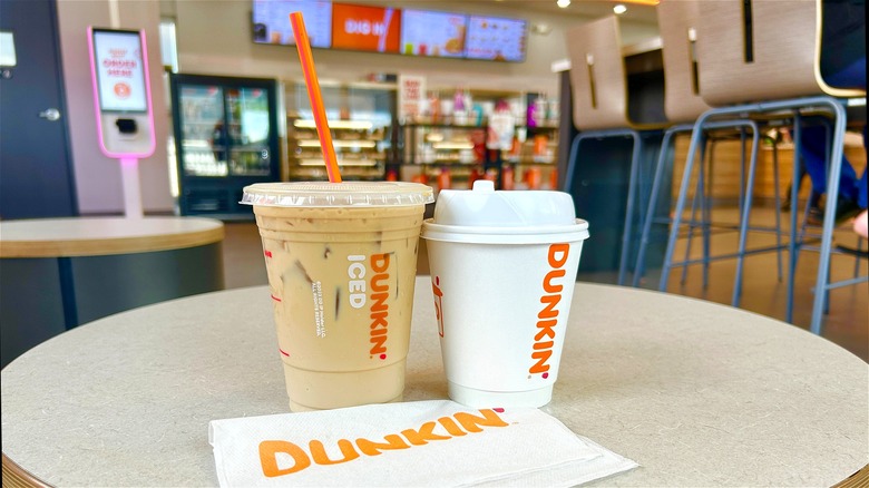 two Dunkin' cups on table