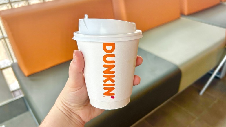 hand holding Dunkin' coffee cup