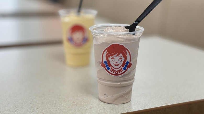 Wendy's chocolate Frosty in front of Salted Caramel Frosty