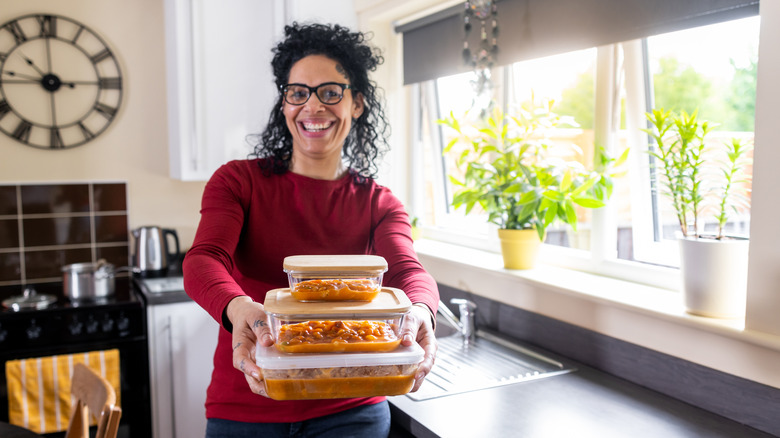 A woman holding three plastic containers full of food