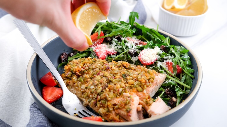 pistachio crusted salmon in bowl with arugula salad