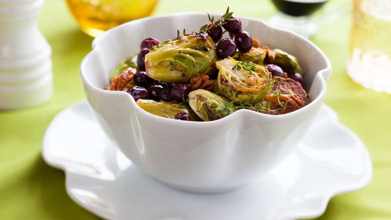 roasted brussels sprouts in white bowl with grapes and thyme