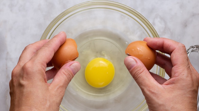 brown egg cracked into a glass bowl