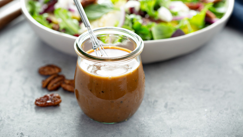 jar of vinaigrette in front of salad