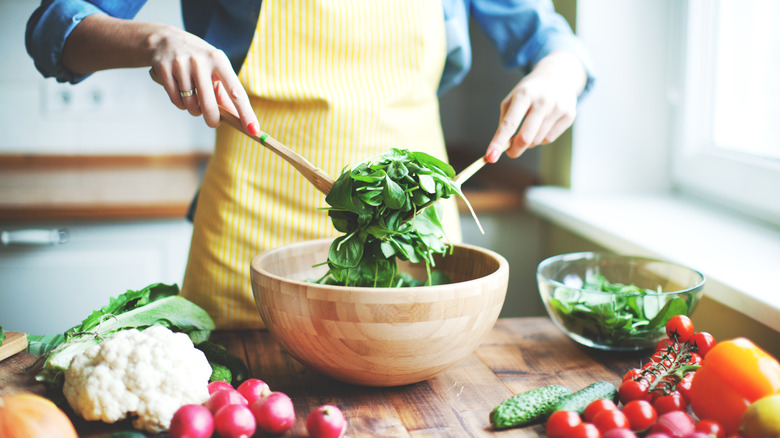 woman tossing bowl of spinach