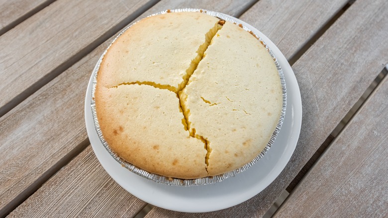 Cracked cake in foil on wooden background