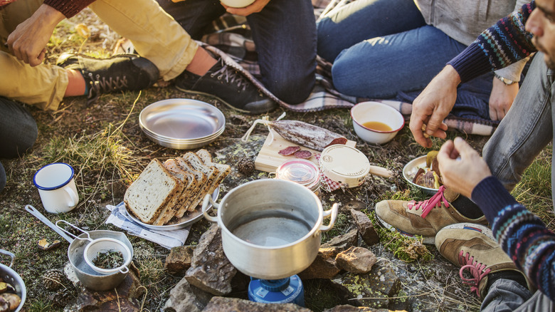 Five people gathered around camping food