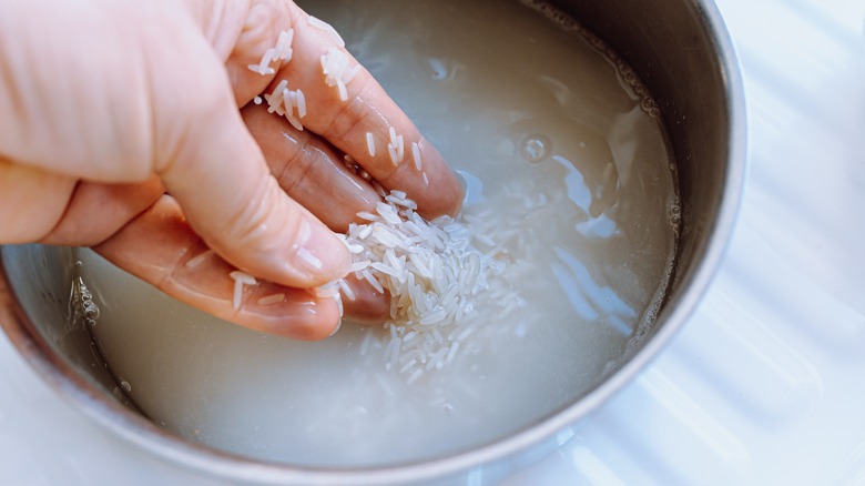 hand rinsing rice grains in bowl