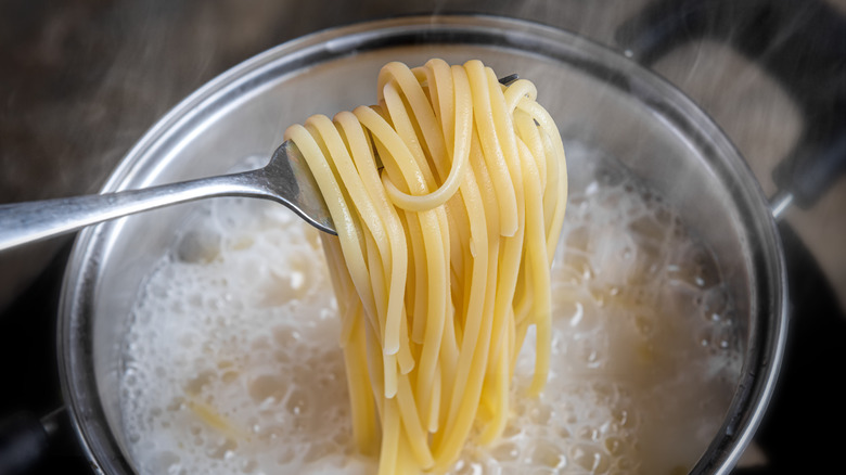 Pasta noodles being removed from boiling water.