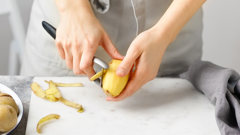 Person peeling potatoes