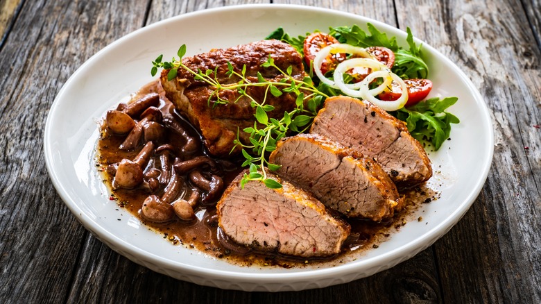 Plate with meat, mushrooms, salad and gravy