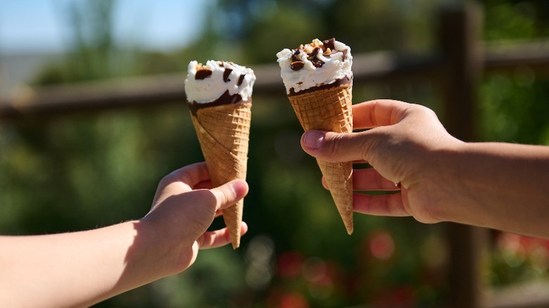 two kids' hands holding ice cream cones