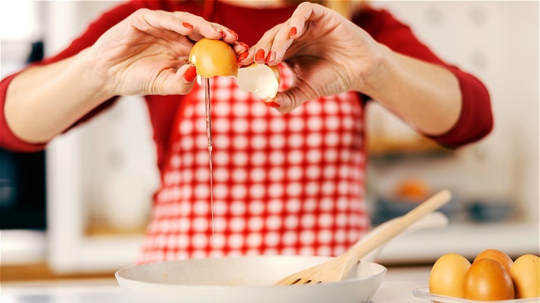 Hands cracking egg into pan 