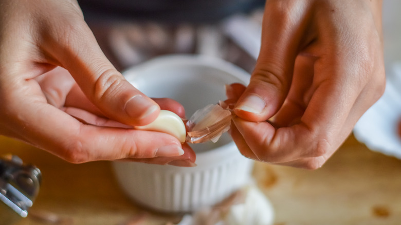 Hands peel clove of garlic