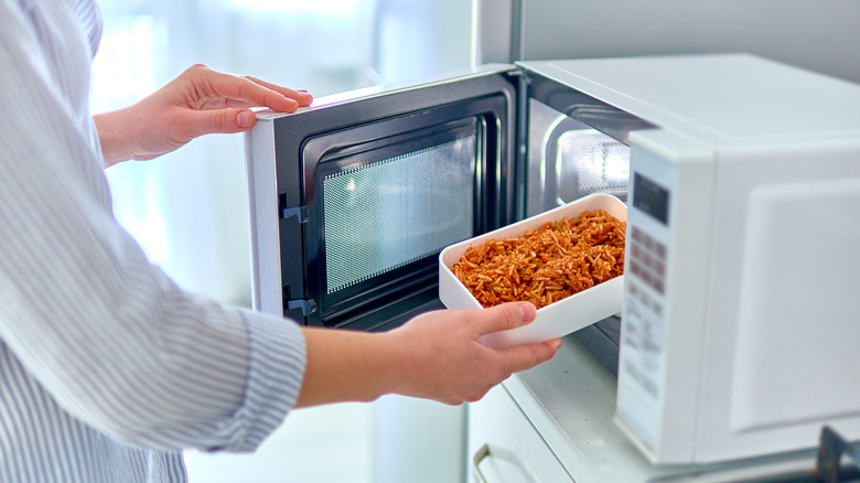 person heating food in microwave