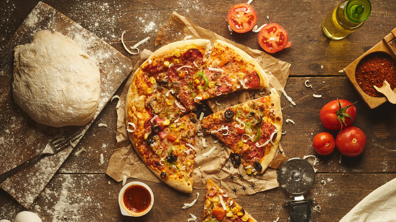 Pizza and ingredients on wooden table