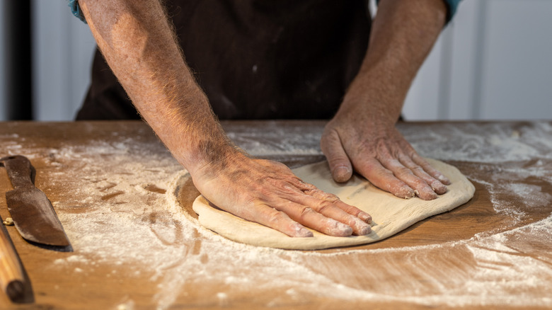 Hands kneading dough on counter