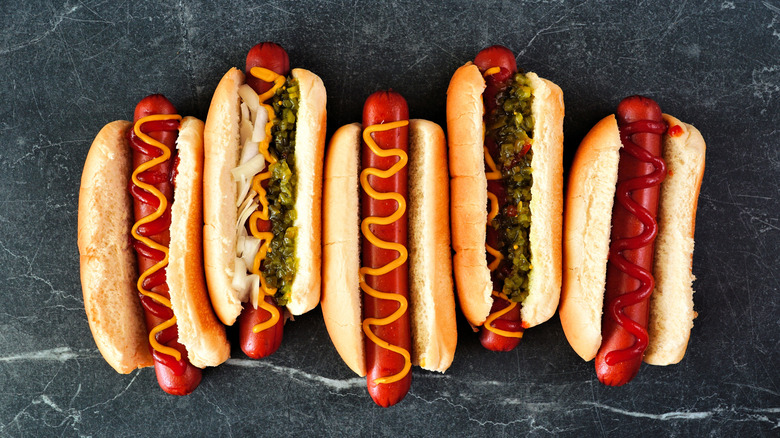 overhead shot of a variety of unique hot dogs on a slate background