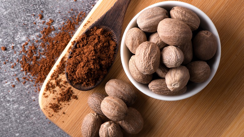 Ground and whole nutmeg on wooden board