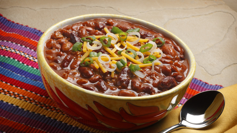 Bowl of chili with cheese and green onion