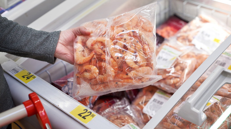 hand holding bag of frozen shrimp at store