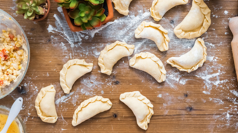 Flour-dusted work surface with uncooked empanadas