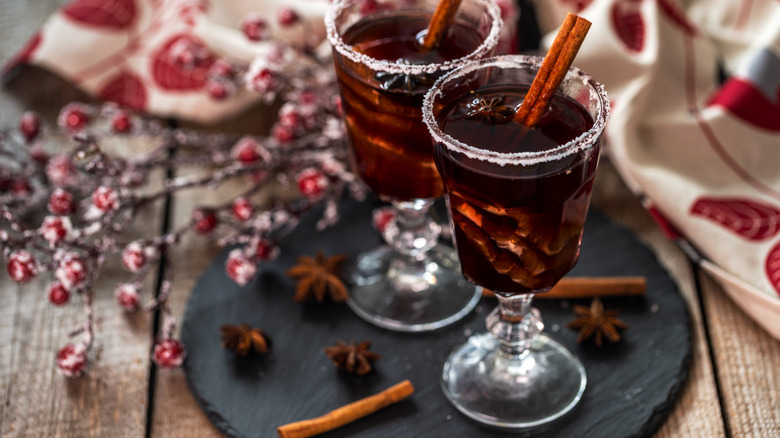 Deep red-brown mulled wine in glass goblets with cinnamon sticks