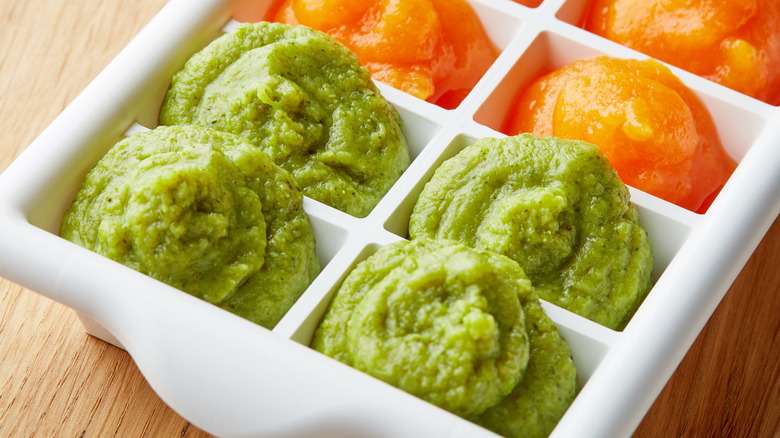 Mashed avocado and carrots in an ice cube tray 