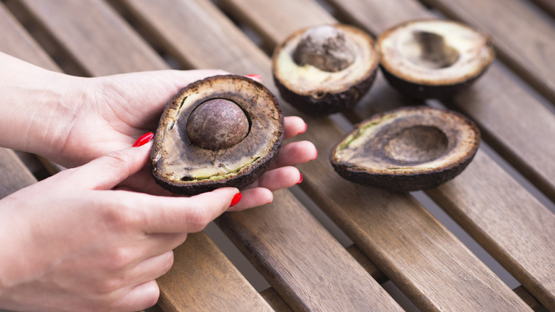 Woman holding a brown avocado in her hand