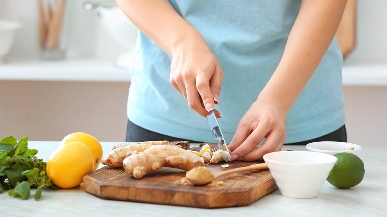 person slicing ginger on cutting board