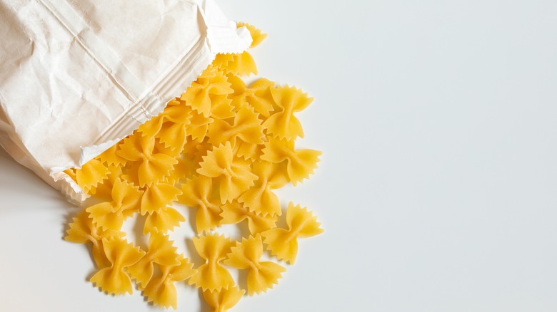 farfalle pasta spills out of paper bag onto white surface