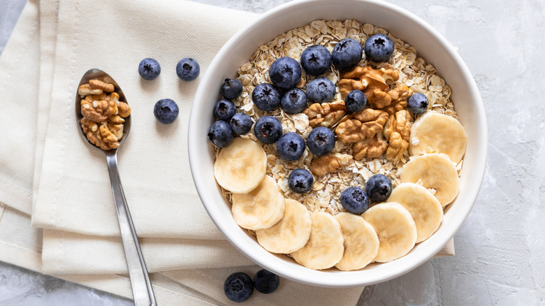 Bowl of oats with banana slices, blueberries, and nuts