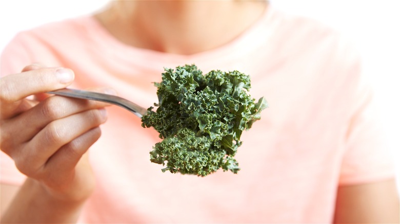 Hand with forkful of raw kale 