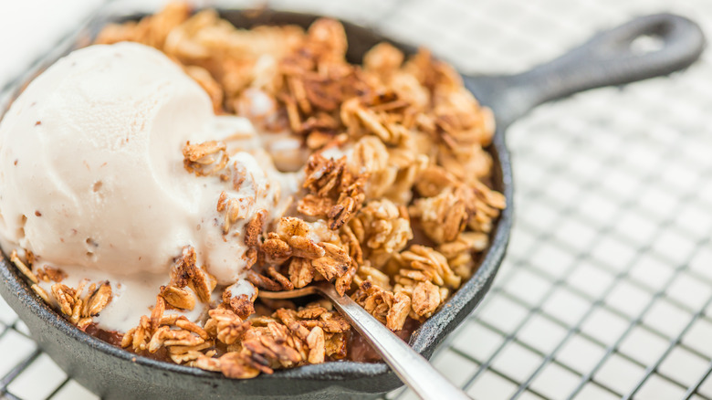 apple cobbler in a cast iron pan with ice cream on top