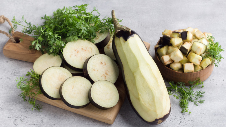 Peeled, sliced, and cubed eggplant on a wooden board