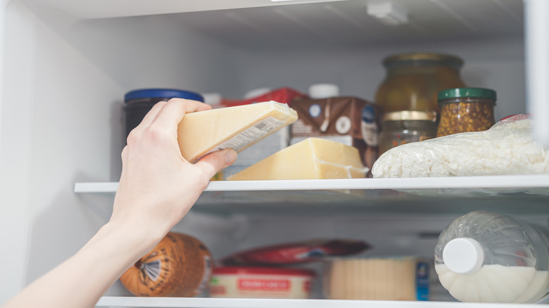 Person putting cheese in fridge